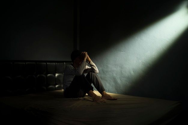 Sad man on the bed in the dark room | Premium Photo