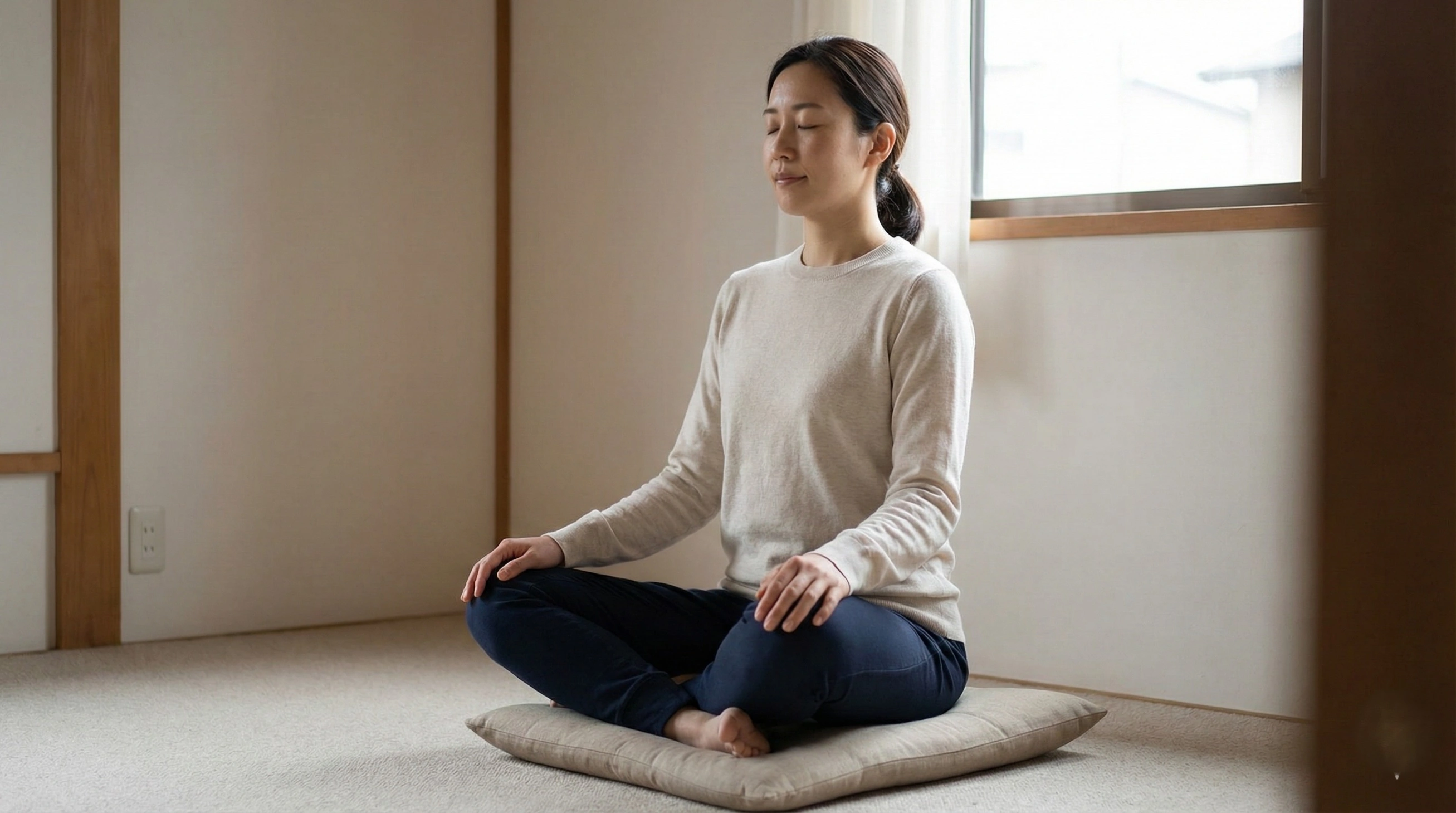 A woman sitting on a cushion indoors practicing simple mindful breathing, illustrating an accessible way for beginners to join World Meditation Day 2025.
