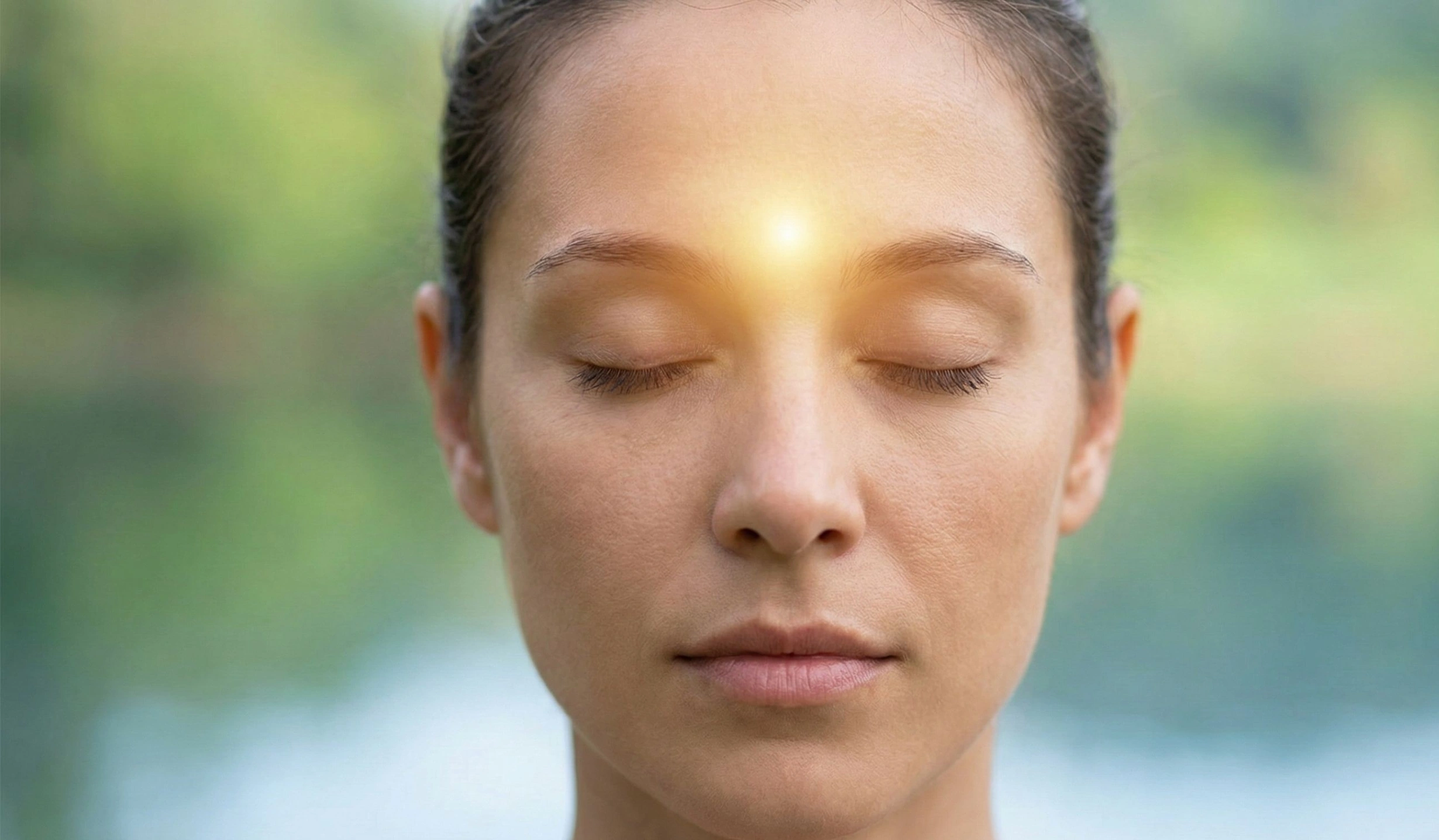 Close-up of a woman in deep meditation with a warm, glowing light centered between her eyebrows, illustrating third eye point focus.