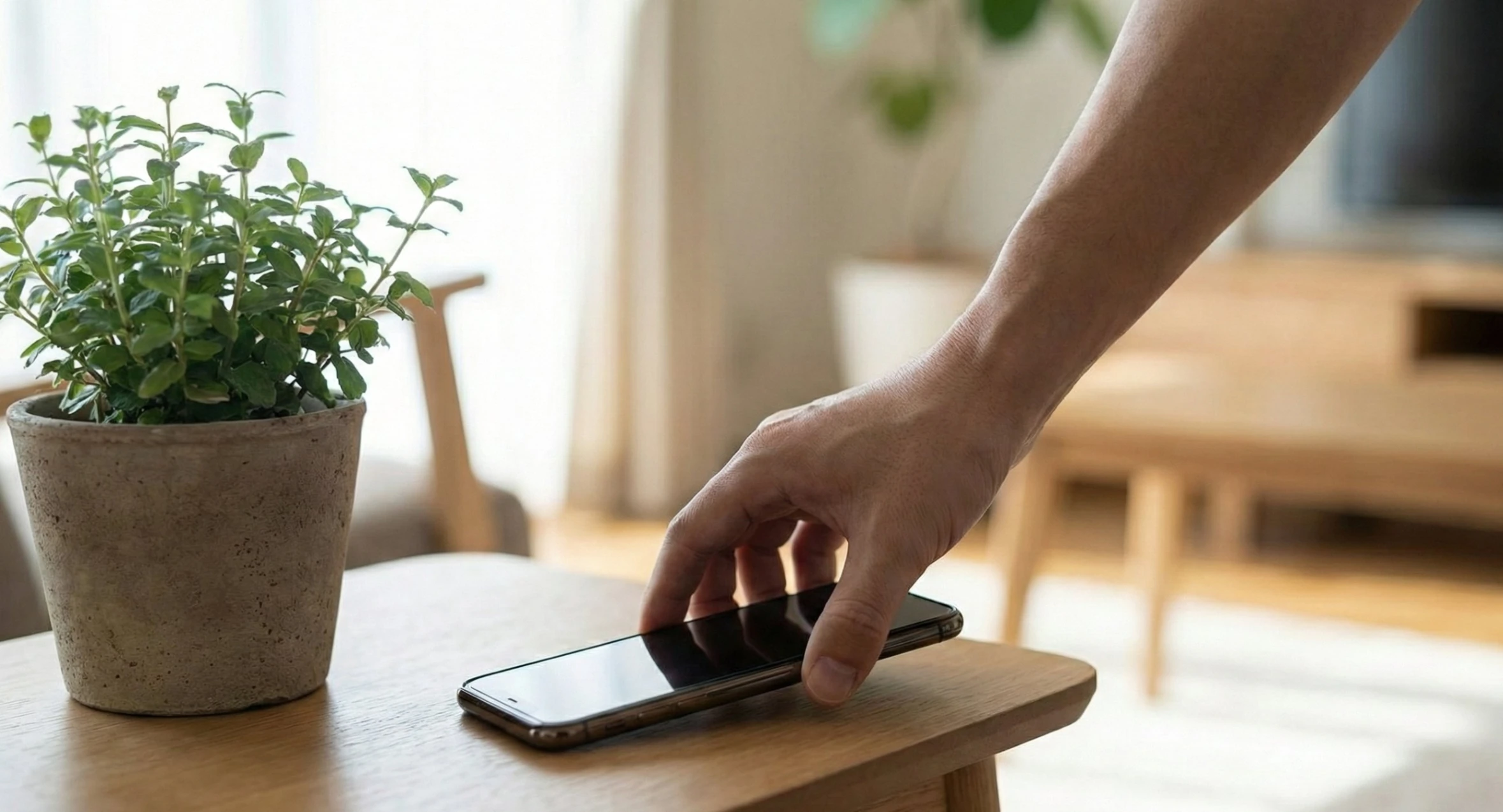 A hand deliberately placing a smartphone face-down on a table, away from distractions